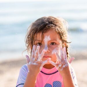Kids Mineral Sunscreen SPF 30 - Girl playing with kids sunscreen all over face on beach in mexico - Suntribe Reef Safe Mineral Sunscreen @Jessfotog